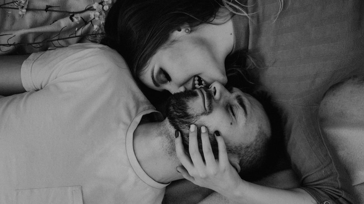 Intimate black and white photo of a couple lying down and sharing a tender moment.
